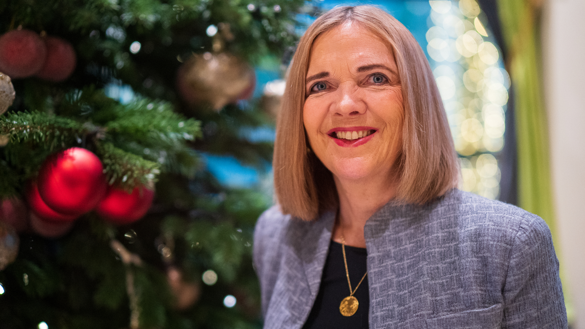 Foto av kvinne, Inga Bolstad, ved siden av et pyntet juletre.