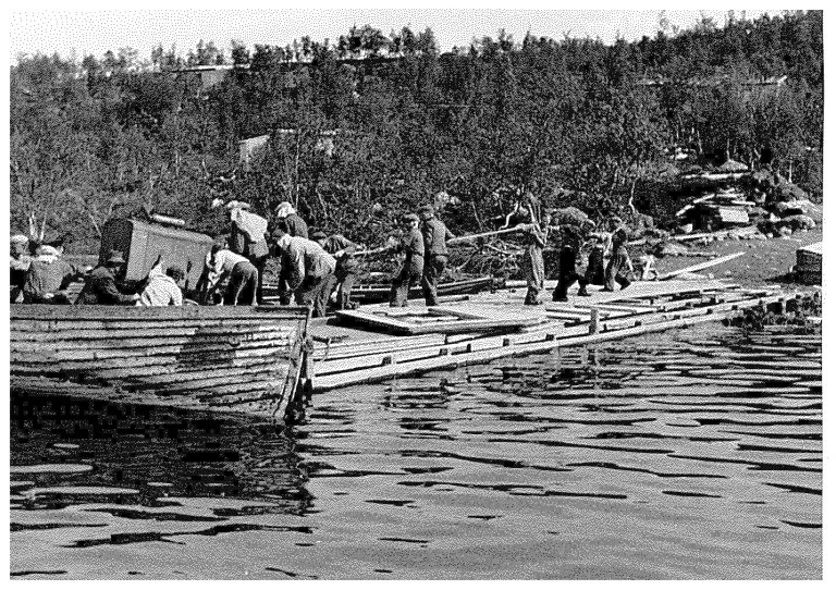 Dei norske eksilstyresmaktene publiserte i 1943 i London dette biletet som Norwegian Official Photo No. L.7645. Teksten bak på biletet lyder: ” ”På tysk tvangsarbeide. Dette bilde er tatt av norske fanger som er hentet ut fra konsentrasjonsleirene for å utføre veiarbeide for tyskerne i Nord-Norge. En ser folk og redskaper bli bragt med båt til arbeidsplassen. ” RA/PA 1209 NTBs krigsarkiv/ Ue/0098.