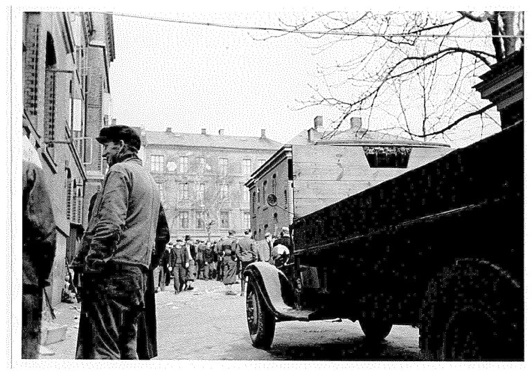 Også dette biletet er publisert av dei norske eksilstyresmaktene i London i 1943, som Norwegian Official Photo No. S.1247A. Teksten bak på biletet lyder: ”Tvangsutskrivningen av norsk arbeidskraft. Dette bilde er tatt inne på gårdsplasssen på Grünerløkken skole i Oslo som er samlingsstedet for tvangsutskrevne nordmenn. Nordmennene sees her sammen med krigsfanger som arbeider for organisasjonen Todt.” RA/PA 1209 NTBs krigsarkiv/Ue/0098.