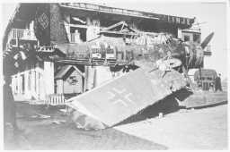 SMADRET: Restene av Den Norske Amerikalinjes bygg på Skoltegrunnskaien. Rett foran bygget er et skadet tysk observasjonsfly av typen Arado 196. Flyet var om bord i den tyske krysseren «Königsberg» som ble satt i brann av allierte fly og sank ved Skoltegrunnkaien 10. april 1940. Selv om flyet ser ødelagt ut, skal det senere ha blitt satt i stand.  FOTO: UKJENT UTLÅN: NTBS KRIGSARKIV/ARKIVVERKET