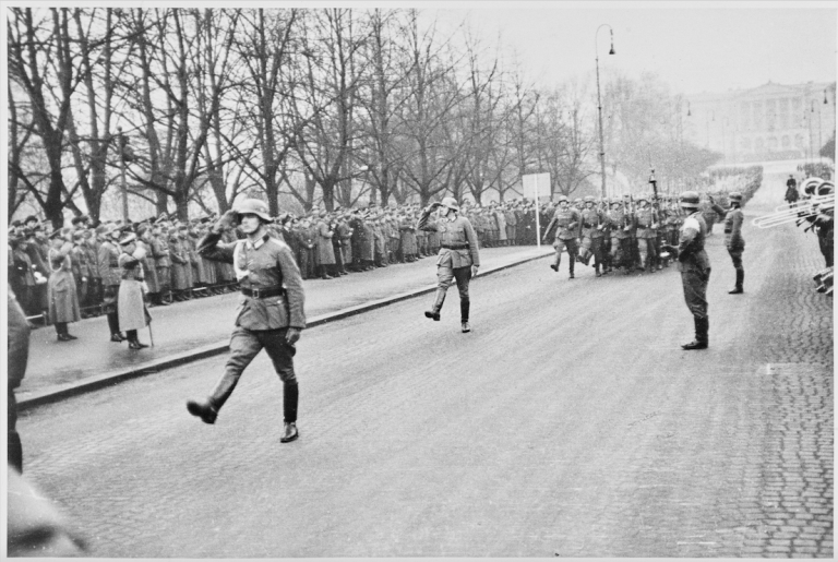Tyske soldater marsjerer på Karl Johan i Oslo, april 1940.  Foto: Arkivverket/Riksarkivet/NTBs krigsarkiv. Arkivreferanse RA/PA-1209/U/Uj/L0219b.