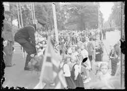 Fra feiringen av kong Haakons 70-årsdag: En del av barna i folketoget foran kongetribunen. Fotograf ukjent. 