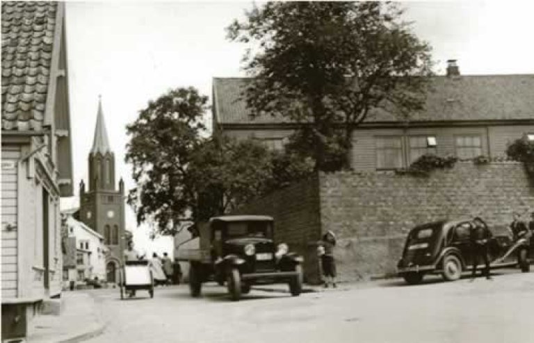 Amtssjukehuset på St. Pedersgjerde bak det høge gjerdet til høgre. Den store to-etasjes trebygningen vart fotografert om lag 1930 før han skulle rivast for å gje plass til Stavanger Tinghus. Sjukehuset låg til Bergelandsgata og hadde St. Petri kirke i nabolaget. Dette første fylkeskommunale sjukehuset vart ferdig i 1843 og var sjukehuset til folk på landsbygda i heile fylket fram til det nye Rogaland Sjukehus stod ferdig i 1927. Foto: G. Wareberg. Statsarkivet i Stavanger.